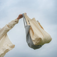 femme tiens deux sacs devant le ciel