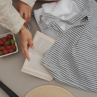 femme au de la piscine avec un livre, des fraises et un sac rayé marine
