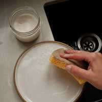 main nettoie assiette avec éponge