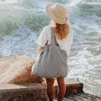 Femme porte sac rayé devant la mer