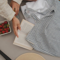 femme au de la piscine avec un livre, des fraises et un sac rayé marine