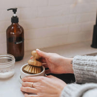 Femme qui met une brosse en bois dans un égouttoir en céramique