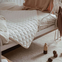 tapis de jeu blanc sur un lit avec des jouets en bois