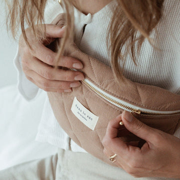 gros plan sur une femme portant un sac banane en tissu matelassé