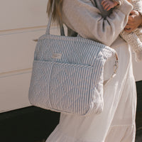 femme porte un sac à couche rayé bleu sur l'épaule