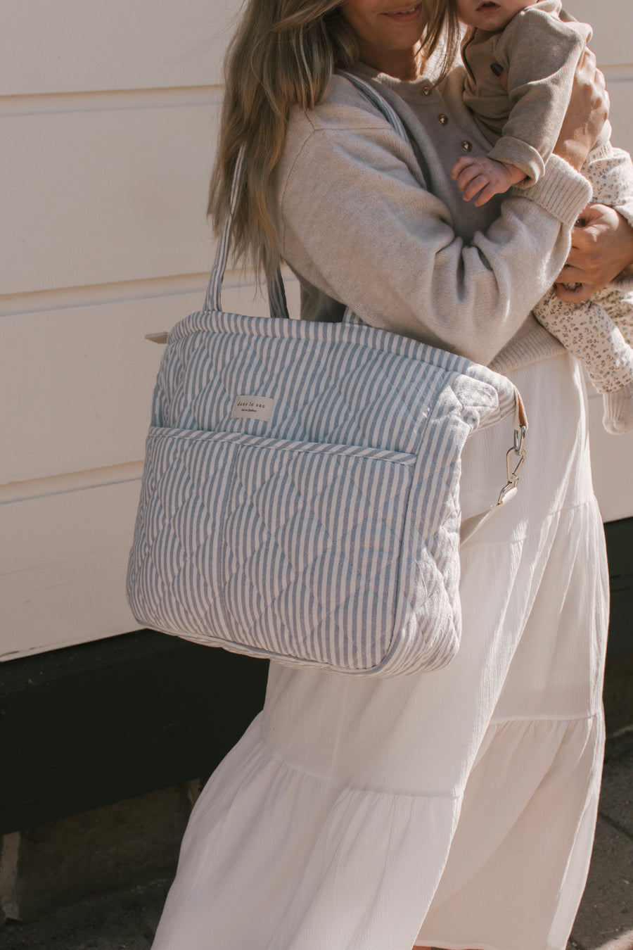 femme porte un sac à couche rayé bleu sur l'épaule