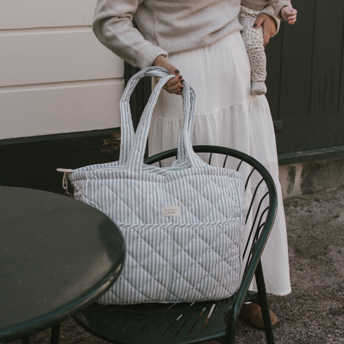 sac à couches rayé bleu sur une chaise extérieure