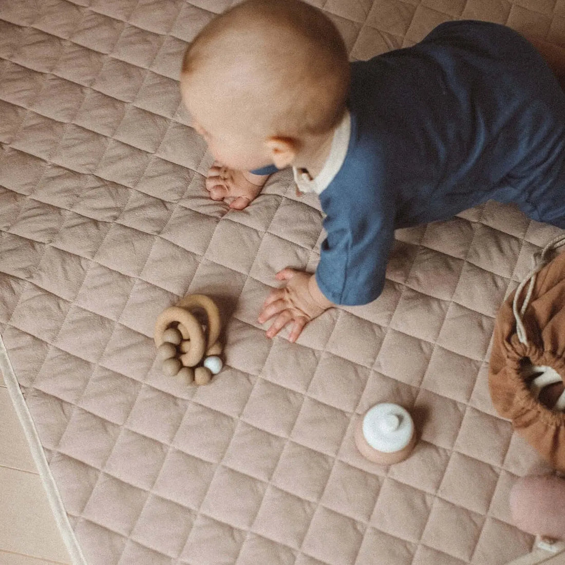 bébé à 4 pattes sur un tapis de jeu neutre