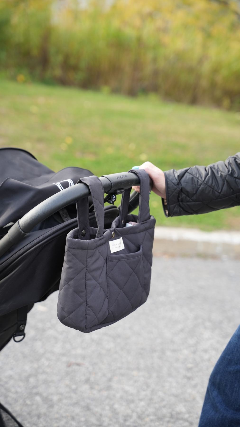Organisateur de poussette matelassé couleur ardoise de Dans le sac, confectionné au Québec avec des tissus Canada Goose récupérés, suspendu à une poussette noire.