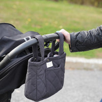 Organisateur de poussette matelassé couleur ardoise de Dans le sac, confectionné au Québec avec des tissus Canada Goose récupérés, suspendu à une poussette noire.