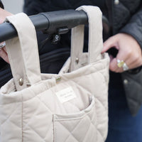 Organisateur de poussette matelassé couleur avoine de Dans le sac, confectionné au Québec avec des tissus Canada Goose récupérés, fixé à une poussette.