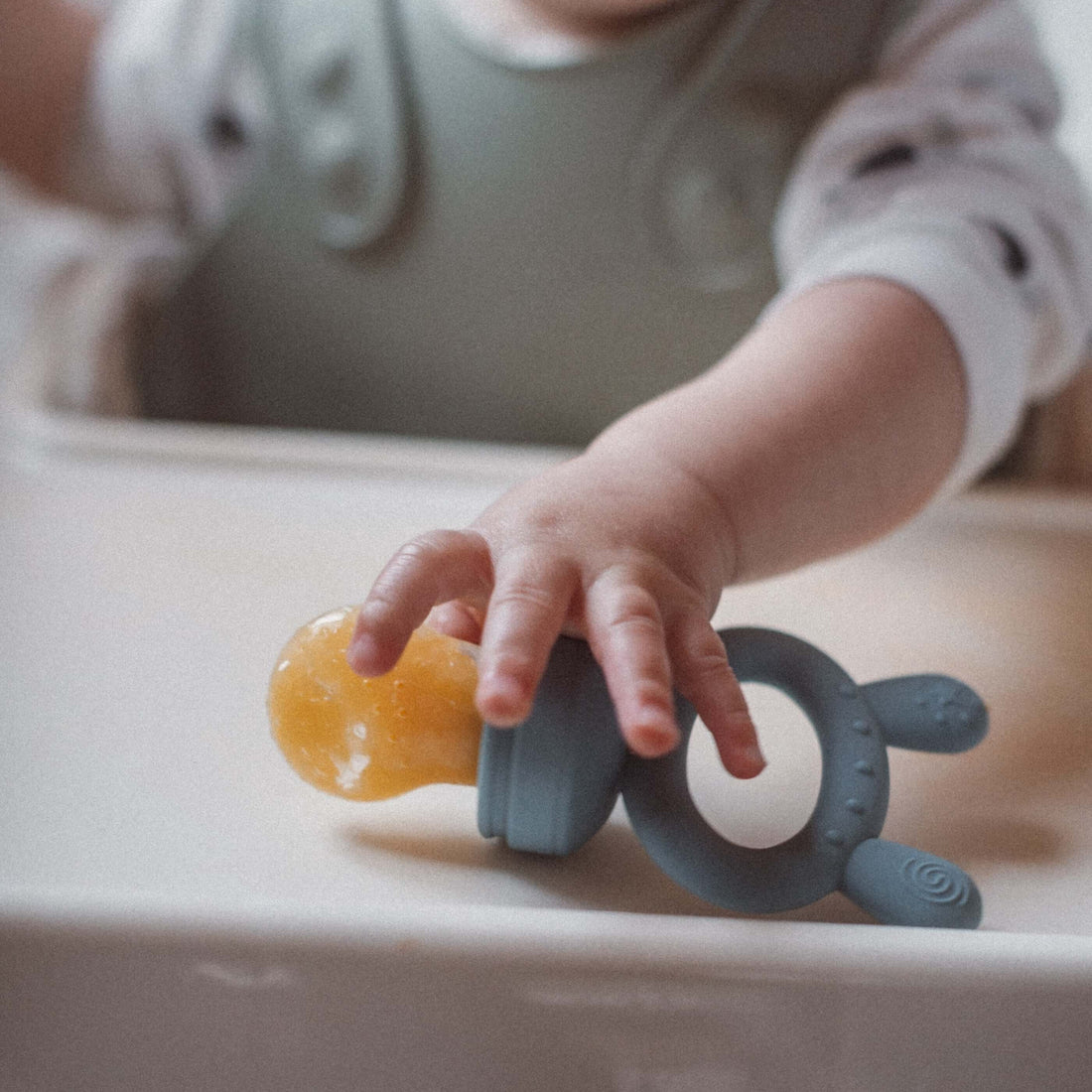main de bébé sur une tétine alimentaire de couleur bleu