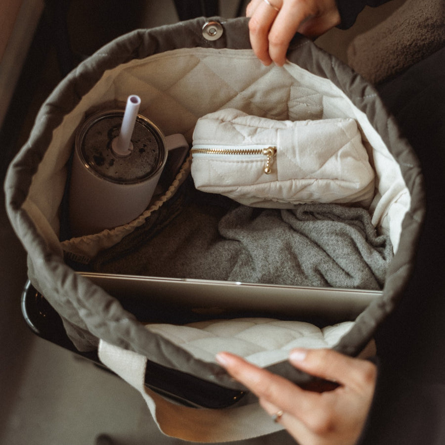 femme qui range son ordinateur, sa bouteille d'eau et une pochette dans le fourre-tout matelassé