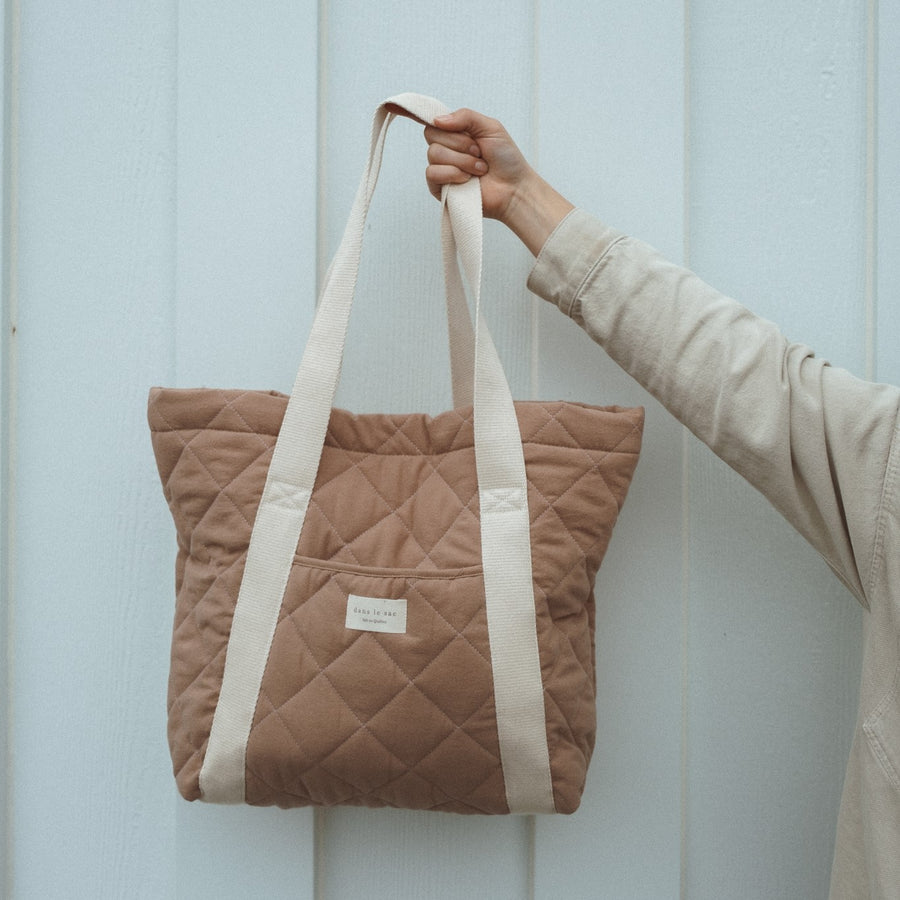 main tient un sac matelassé beige