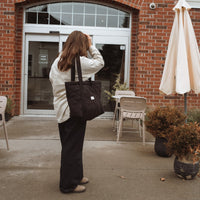 femme marche en tenant un sac noir