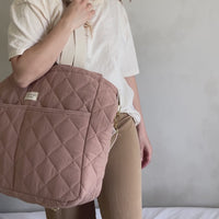 femme avec un grand sac à couche et différents produits d'organisation pour bébé