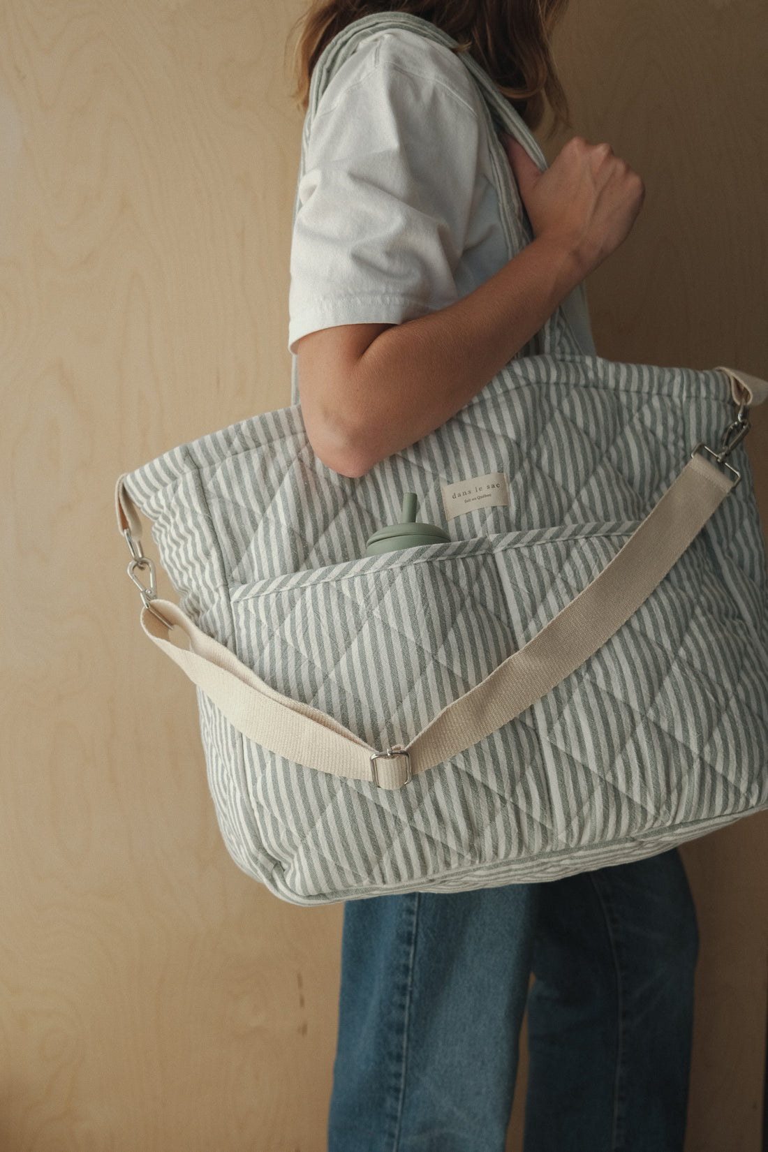 femme porte un sac à couche rayé sauge sur l'épaule