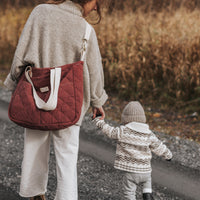 Femme porte un sac à l'épaule et tien la main d'un enfant